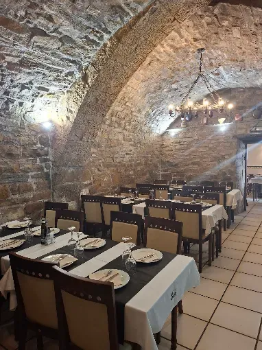 Comedor bajo bóvedas de piedra con mesas vestidas de blanco y luz cálida