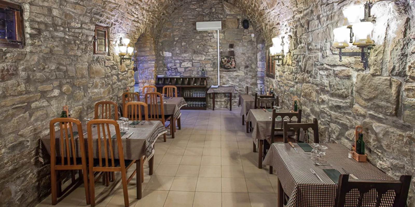 Comedor de paredes de piedra con mesas de mantel de cuadros